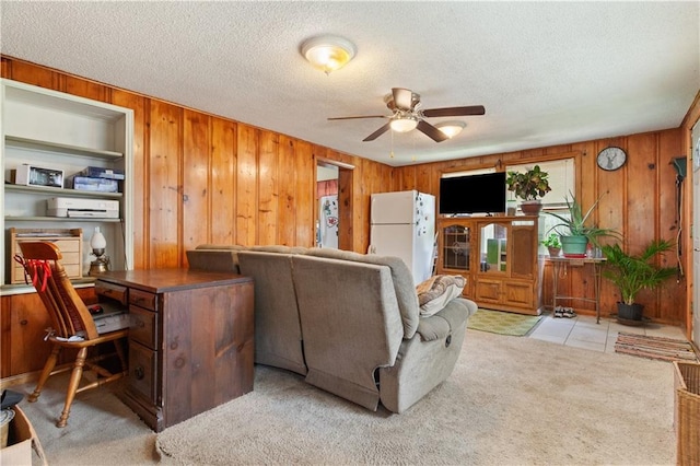225 W Moore St, Independence, MO 64050 - living room featuring wooden walls, ceiling fan, a desk, a textured ceiling, and light colored carpet