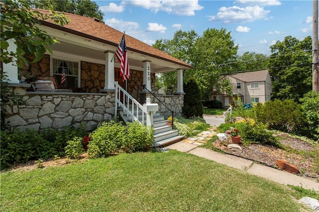 225 W Moore St, Independence, MO 64050 - view of front of home featuring stone siding, a porch, a front yard, and a shingled roof