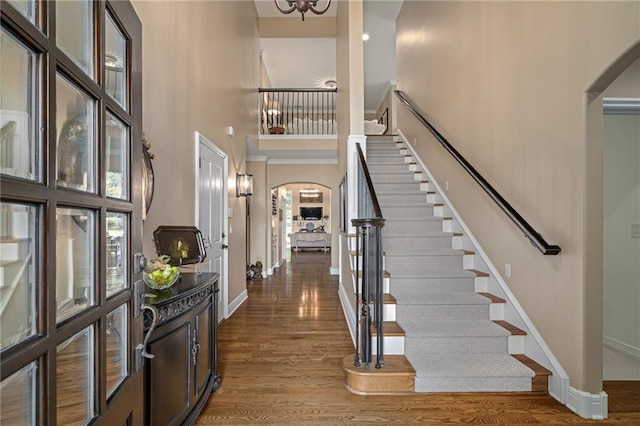 14208 Larsen St, Overland Park, KS 66221 - foyer entrance featuring arched walkways, a towering ceiling, stairs, and wood finished floors