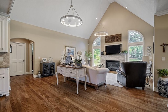 14208 Larsen St, Overland Park, KS 66221 - living room with high vaulted ceiling, a fireplace, dark wood-style floors, arched walkways, and a chandelier