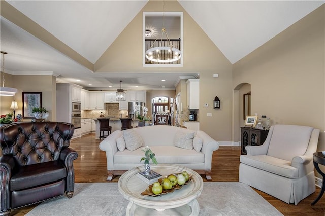 14208 Larsen St, Overland Park, KS 66221 - living room featuring a chandelier, arched walkways, wood finished floors, high vaulted ceiling, and recessed lighting