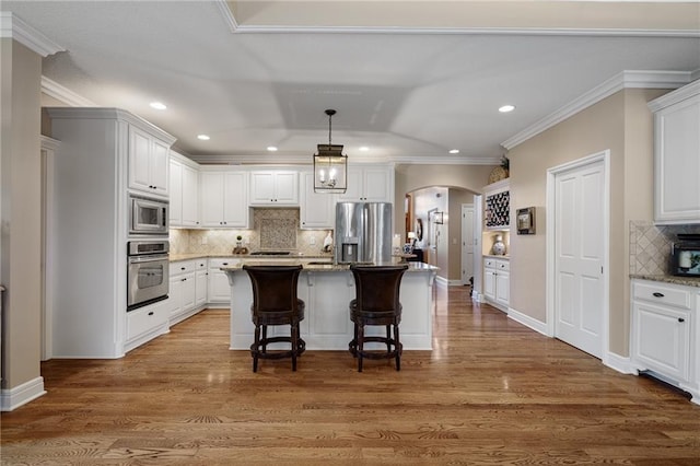 14208 Larsen St, Overland Park, KS 66221 - kitchen featuring stainless steel appliances, arched walkways, tasteful backsplash, white cabinets, and recessed lighting