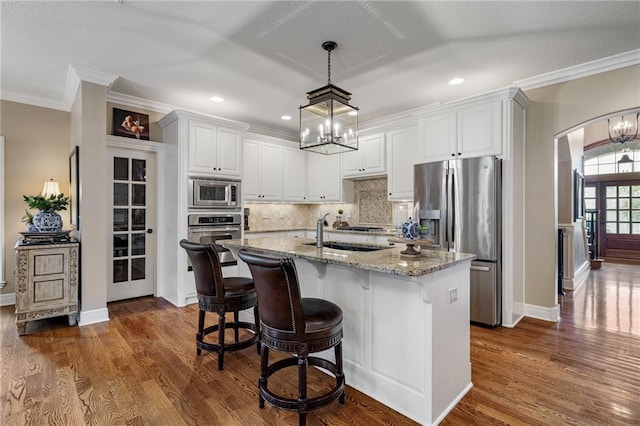 14208 Larsen St, Overland Park, KS 66221 - kitchen featuring appliances with stainless steel finishes, a chandelier, backsplash, dark wood finished floors, and crown molding