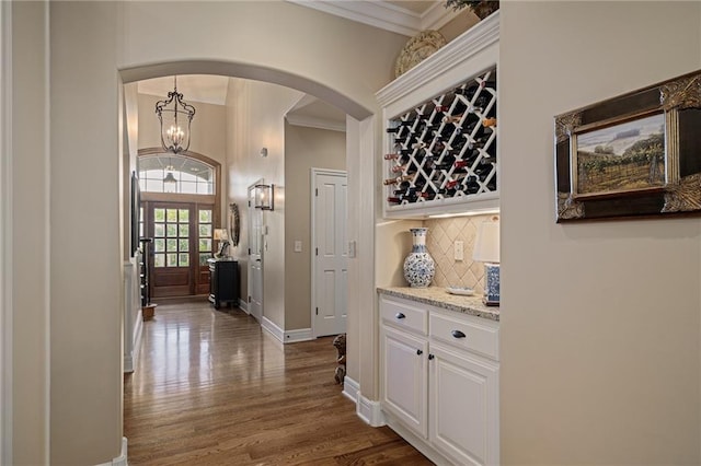14208 Larsen St, Overland Park, KS 66221 - corridor featuring arched walkways, ornamental molding, dark wood-type flooring, and a chandelier