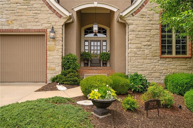 14208 Larsen St, Overland Park, KS 66221 - view of exterior entry featuring stone siding, an attached garage, stucco siding, and driveway