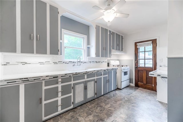 6645 Cherry St, Kansas City, MO 64131 - kitchen featuring white gas stove, gray cabinets, decorative backsplash, under cabinet range hood, and a ceiling fan