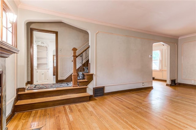 6645 Cherry St, Kansas City, MO 64131 - unfurnished living room featuring arched walkways, wood finished floors, stairway, and ornamental molding