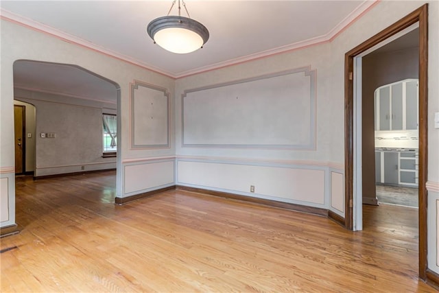 6645 Cherry St, Kansas City, MO 64131 - spare room with light wood-style flooring, arched walkways, crown molding, wainscoting, and a decorative wall