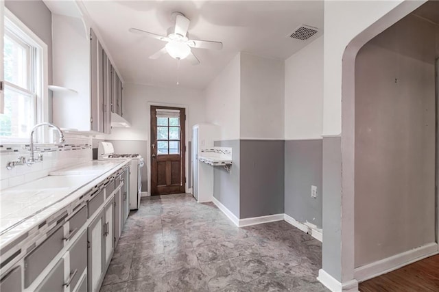 6645 Cherry St, Kansas City, MO 64131 - kitchen with white gas range, ceiling fan, under cabinet range hood, arched walkways, and tile counters