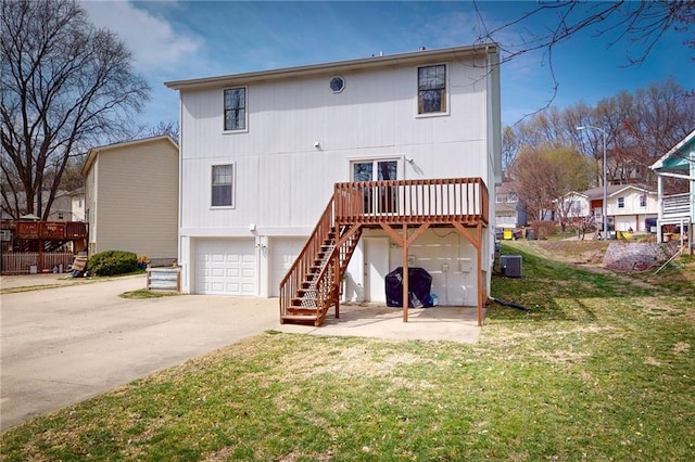 334 Fawn Valley Ct, Lansing, KS 66043 - back of house featuring an attached garage, a wooden deck, driveway, stairway, and a lawn