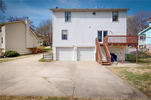 334 Fawn Valley Ct, Lansing, KS 66043 - back of property with a wooden deck, an attached garage, stairway, and concrete driveway