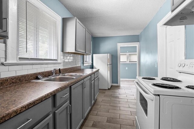 5701 Wabash Ave, Kansas City, MO 64130 - kitchen with white appliances, under cabinet range hood, a sink, gray cabinetry, and dark countertops