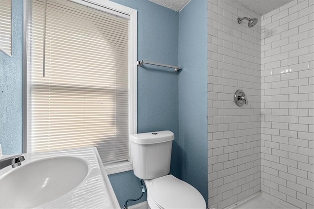 5701 Wabash Ave, Kansas City, MO 64130 - full bath with a tile shower, toilet, a sink, a textured ceiling, and a textured wall
