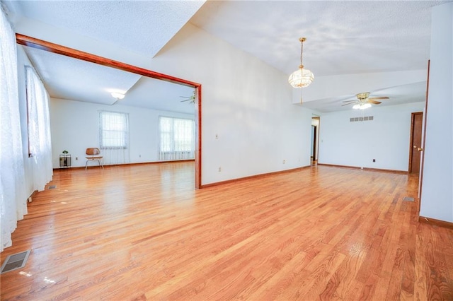 1110 E 1600th Rd, Lawrence, KS 66046 - unfurnished living room with light wood finished floors, a ceiling fan, vaulted ceiling, baseboards, and a chandelier