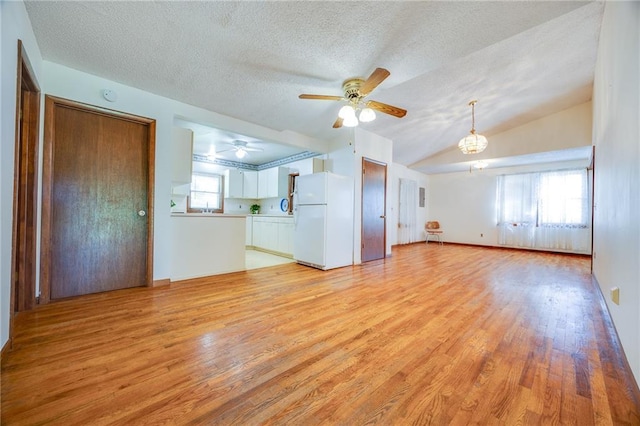 1110 E 1600th Rd, Lawrence, KS 66046 - unfurnished living room with ceiling fan, light wood-style flooring, a textured ceiling, vaulted ceiling, and baseboards