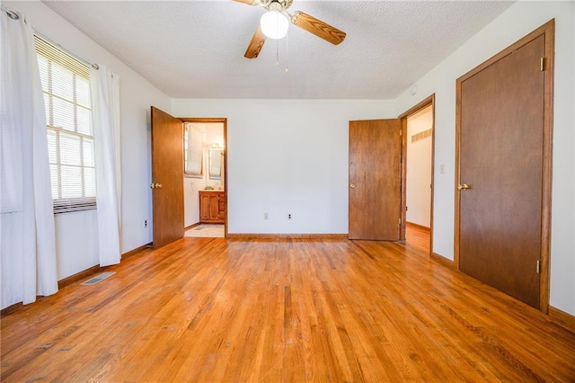 1110 E 1600th Rd, Lawrence, KS 66046 - unfurnished bedroom featuring light wood finished floors, baseboards, ensuite bath, a textured ceiling, and a ceiling fan