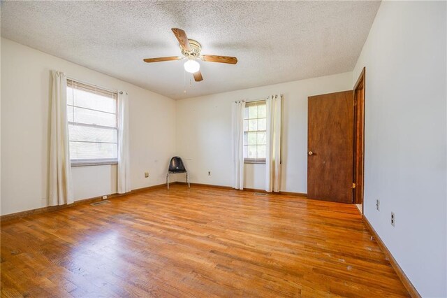 1110 E 1600th Rd, Lawrence, KS 66046 - spare room with light wood-type flooring, a textured ceiling, ceiling fan, and baseboards