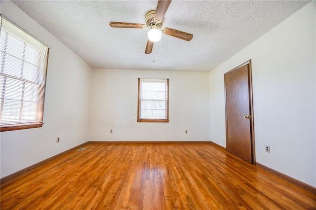 1110 E 1600th Rd, Lawrence, KS 66046 - empty room with hardwood / wood-style floors, a textured ceiling, ceiling fan, and baseboards