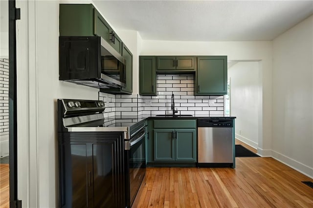 1220 E 24th Ave, Kansas City, MO 64116 - kitchen featuring green cabinetry, black range with electric cooktop, stainless steel dishwasher, a sink, and dark countertops