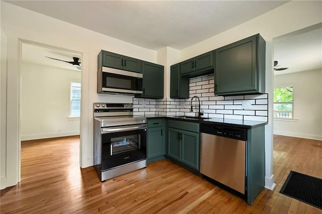 1220 E 24th Ave, Kansas City, MO 64116 - kitchen with appliances with stainless steel finishes, a sink, ceiling fan, and green cabinets