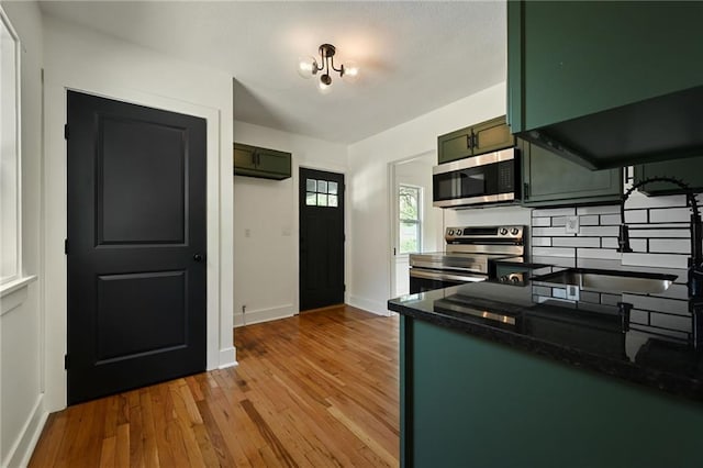 1220 E 24th Ave, Kansas City, MO 64116 - kitchen featuring stainless steel appliances, dark countertops, green cabinetry, light wood-style floors, and baseboards