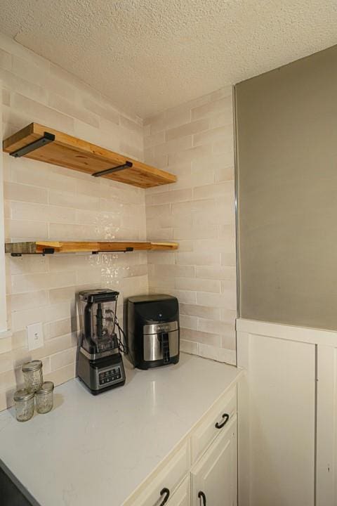 300 Brown Ave, Osawatomie, KS 66064 - kitchen featuring open shelves, light countertops, a textured ceiling, white cabinetry, and backsplash