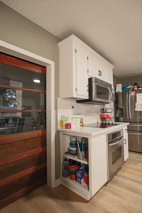 300 Brown Ave, Osawatomie, KS 66064 - kitchen with appliances with stainless steel finishes, white cabinetry, light wood-style flooring, a textured ceiling, and light countertops
