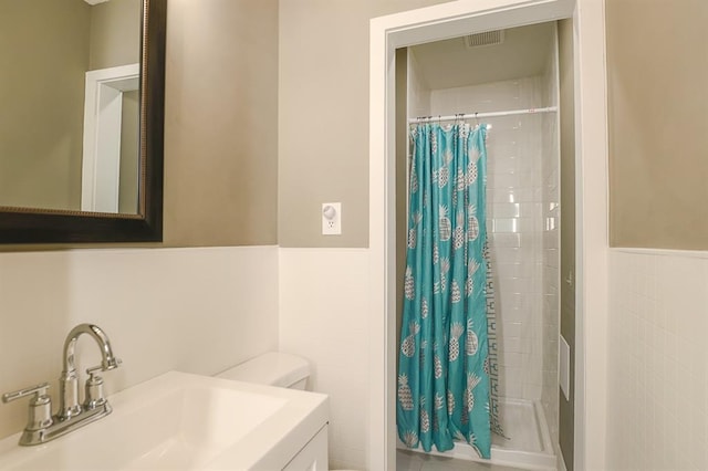 300 Brown Ave, Osawatomie, KS 66064 - bathroom with tile walls, tiled shower, vanity, and wainscoting