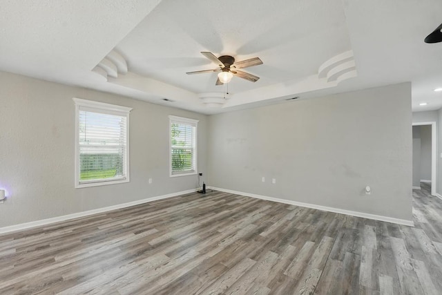 503 N Washington St, East Lynne, MO 64743 - spare room featuring a tray ceiling, ceiling fan, wood finished floors, and baseboards