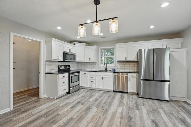 503 N Washington St, East Lynne, MO 64743 - kitchen with stainless steel appliances, dark countertops, light wood-type flooring, backsplash, and recessed lighting