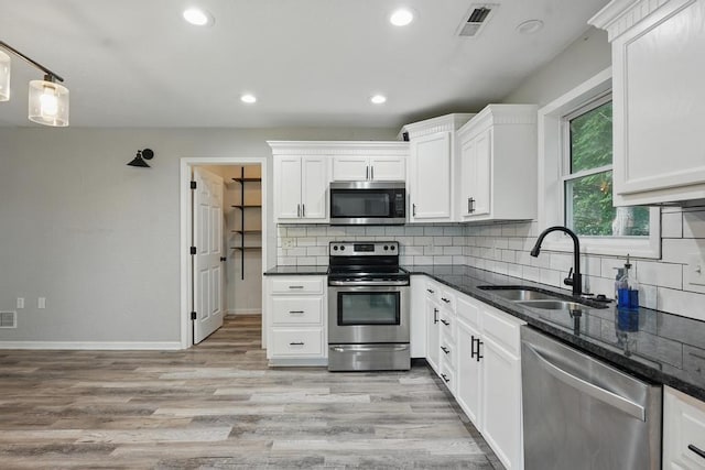 503 N Washington St, East Lynne, MO 64743 - kitchen featuring stainless steel appliances, a sink, white cabinetry, decorative backsplash, and dark stone countertops