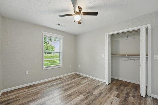 503 N Washington St, East Lynne, MO 64743 - unfurnished bedroom featuring wood finished floors, a closet, baseboards, a ceiling fan, and a textured ceiling