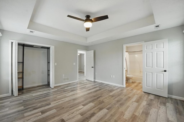 503 N Washington St, East Lynne, MO 64743 - unfurnished bedroom featuring a raised ceiling, wood finished floors, baseboards, and ensuite bathroom