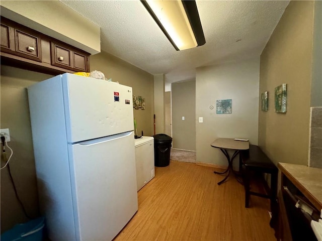 14051 Dunbar Ct, Grandview, MO 64030 - kitchen with freestanding refrigerator, light wood-style flooring, a textured ceiling, and washer / dryer