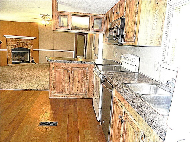 504 N Locust St, Moran, KS 66755 - kitchen with stainless steel appliances, a peninsula, brown cabinetry, dark wood-type flooring, and a textured ceiling