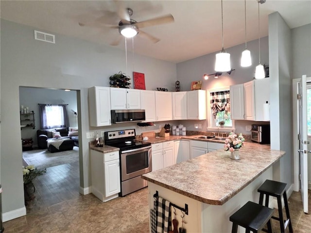 5325 Bryant Bottom Rd, Blackwater, MO 65322 - kitchen featuring appliances with stainless steel finishes, a peninsula, white cabinetry, a breakfast bar, and ceiling fan