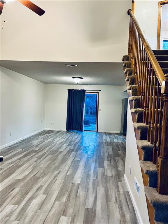 766 Spring Cir, Liberty, MO 64068 - unfurnished living room featuring stairway, wood finished floors, and baseboards