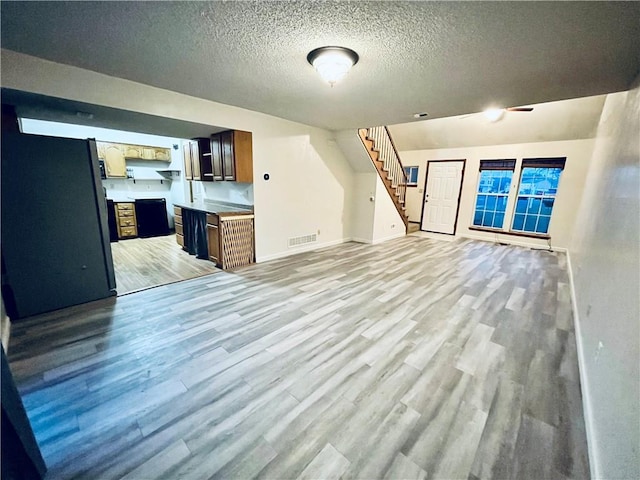 766 Spring Cir, Liberty, MO 64068 - unfurnished living room featuring light wood-type flooring, stairway, a textured ceiling, and baseboards