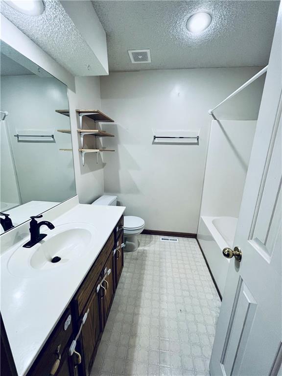 766 Spring Cir, Liberty, MO 64068 - full bathroom featuring a textured ceiling, vanity, toilet, shower / bathtub combination, and tile patterned floors