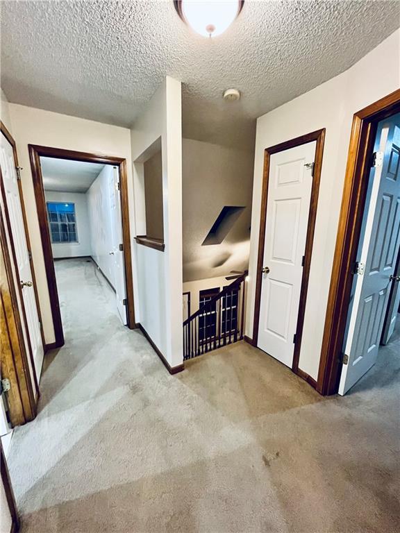 766 Spring Cir, Liberty, MO 64068 - corridor with baseboards, light colored carpet, and a textured ceiling