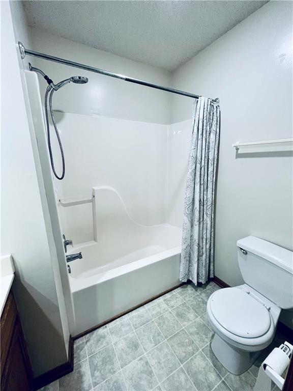 766 Spring Cir, Liberty, MO 64068 - bathroom with a textured ceiling, shower / bath combo with shower curtain, toilet, vanity, and tile patterned flooring