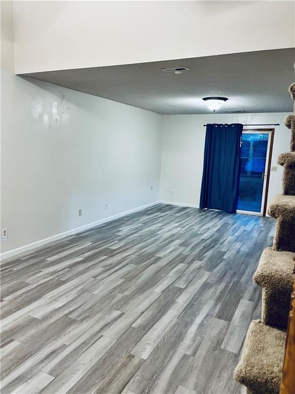 766 Spring Cir, Liberty, MO 64068 - unfurnished living room with wood finished floors, baseboards, and a textured ceiling