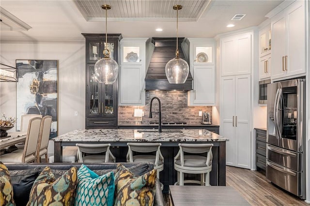 15278 W 173rd St, Olathe, KS 66062 - kitchen with stainless steel appliances, wall chimney exhaust hood, wood finished floors, decorative backsplash, and light stone countertops