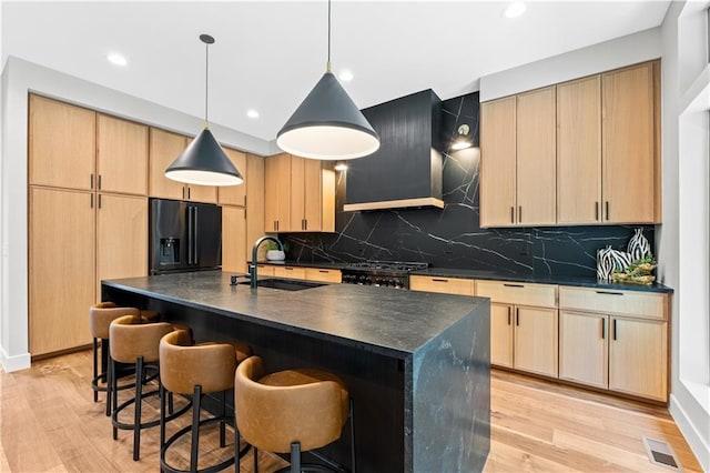 6111 Persimmon Ct, Parkville, MO 64152 - kitchen with a sink, black fridge, dark countertops, wall chimney range hood, and light brown cabinets