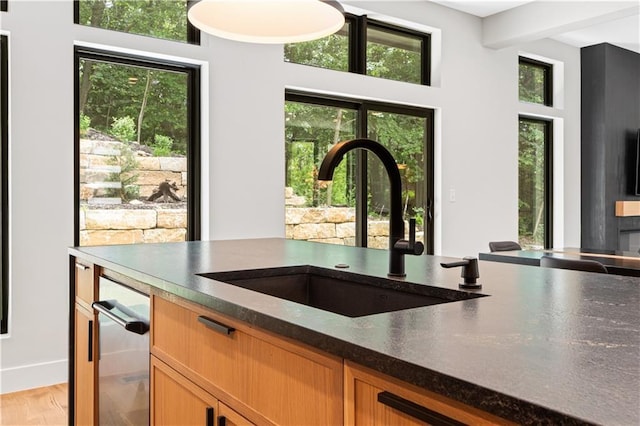 6111 Persimmon Ct, Parkville, MO 64152 - kitchen featuring a sink, plenty of natural light, light wood-type flooring, beamed ceiling, and brown cabinetry
