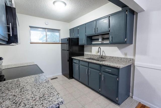 255 N Michigan St Unit 1-2, Lawrence, KS 66044 - kitchen featuring a sink, freestanding refrigerator, a textured ceiling, stove, and blue cabinetry