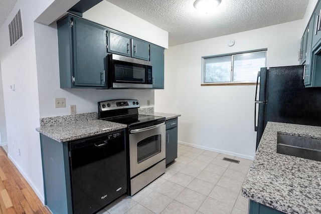 255 N Michigan St Unit 1-2, Lawrence, KS 66044 - kitchen featuring stainless steel appliances, a textured ceiling, light countertops, baseboards, and blue cabinets