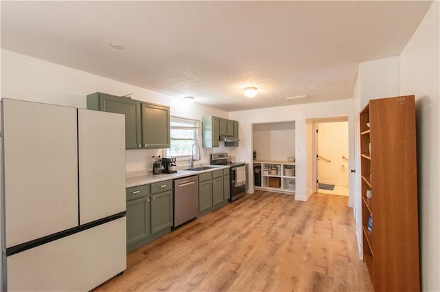 1739 W 26th St, Lawrence, KS 66047 - kitchen with appliances with stainless steel finishes, green cabinetry, light countertops, light wood-style floors, and a textured ceiling