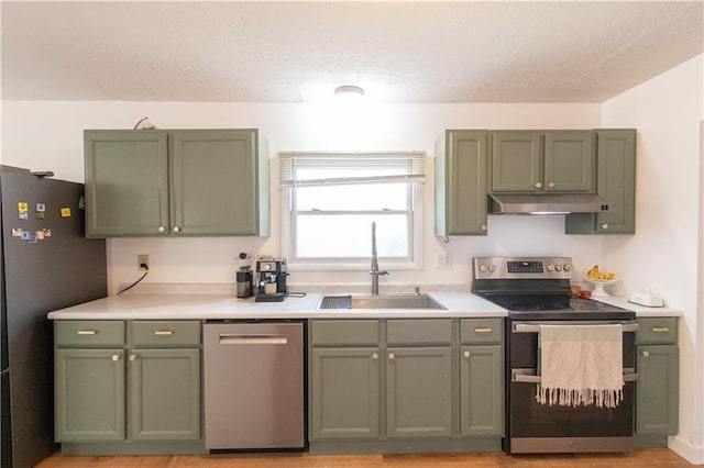 1739 W 26th St, Lawrence, KS 66047 - kitchen with stainless steel appliances, green cabinetry, under cabinet range hood, light countertops, and a textured ceiling