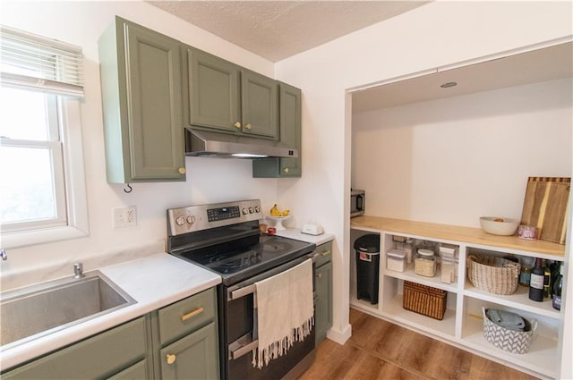 1739 W 26th St, Lawrence, KS 66047 - kitchen featuring stainless steel electric stove, under cabinet range hood, green cabinets, light countertops, and dark wood finished floors